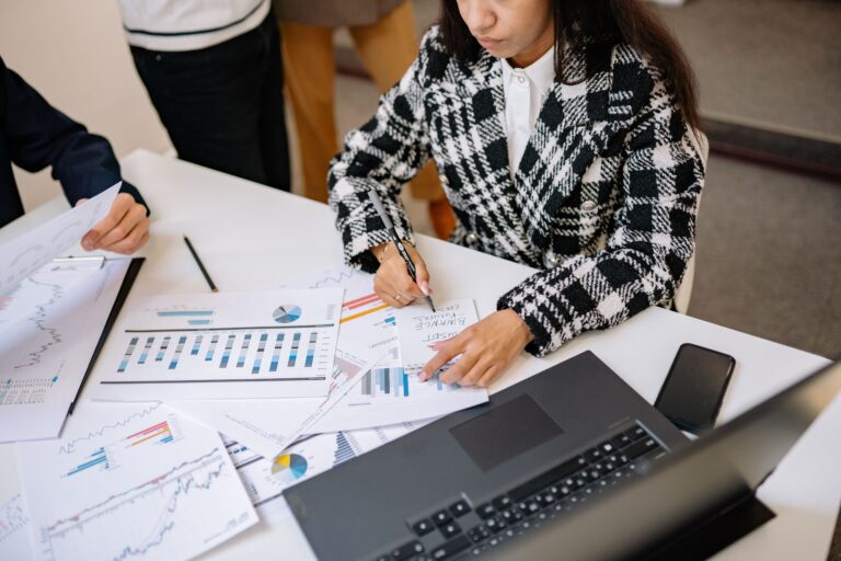Businesswoman reviewing graphs and charts with colleagues, analyzing financial data in a modern office setting.